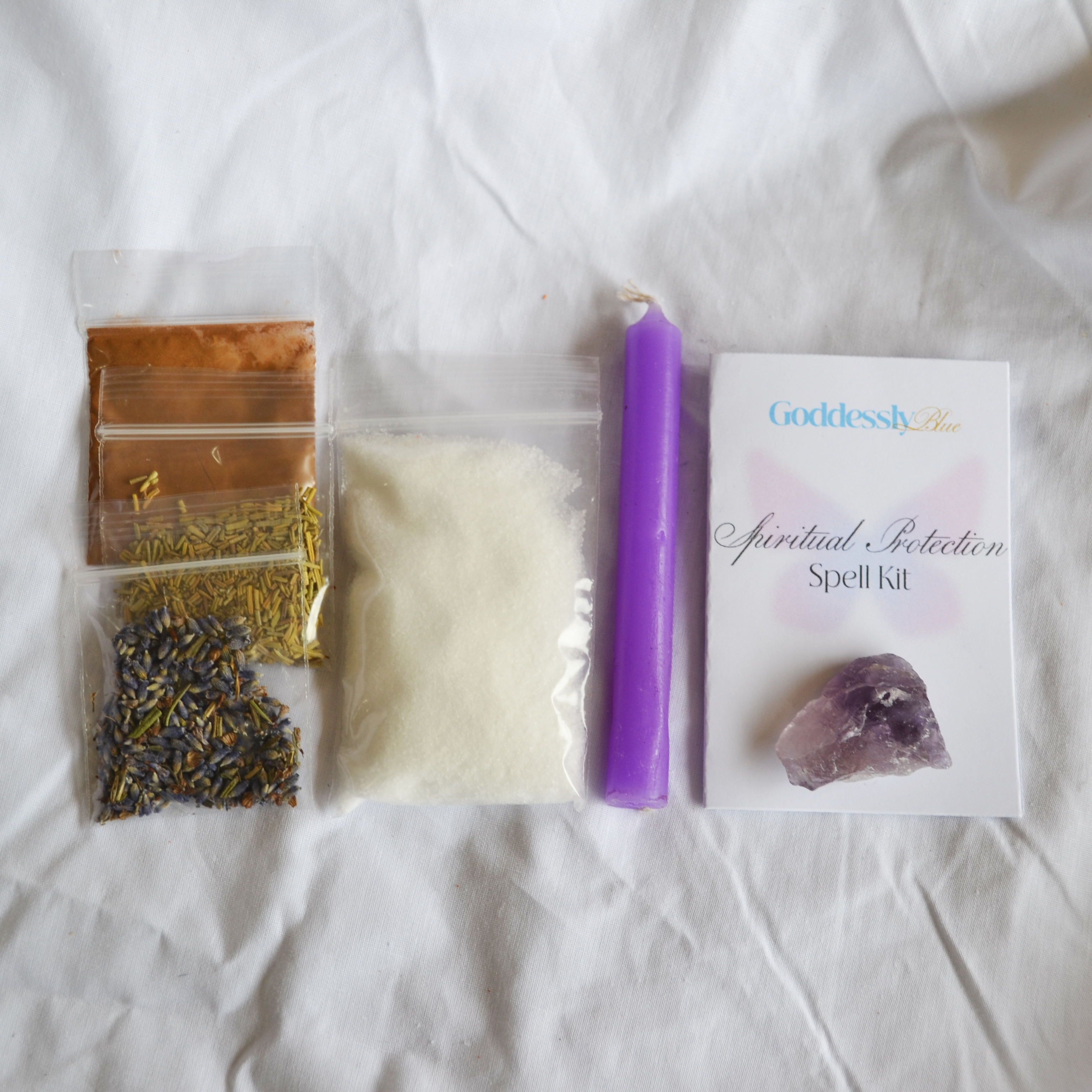 Spiritual Protection spell kit with amethyst crystal, purple wish candle, salt, dried herbs (cinnamon, rosemary and lavender), and card with instructions and affirmation.